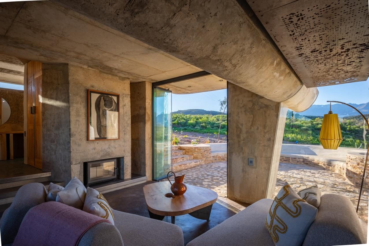Skaapwagtershuisie — living room, concrete vault ceiling, fireplace, sliding glass to Karoo landscape