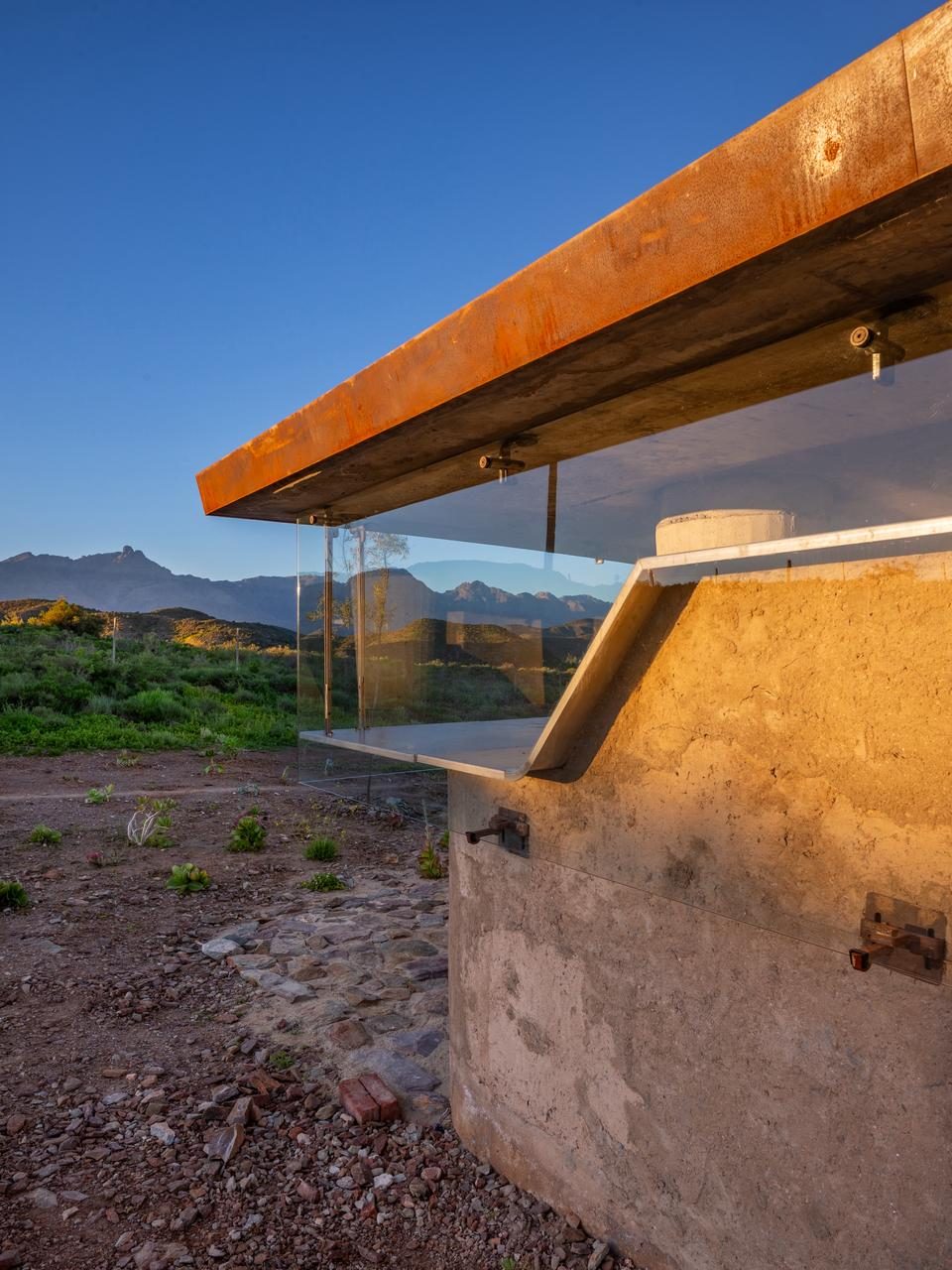 Skaapwagtershuisie — corten steel edge beam, glass wall, mountains at golden hour