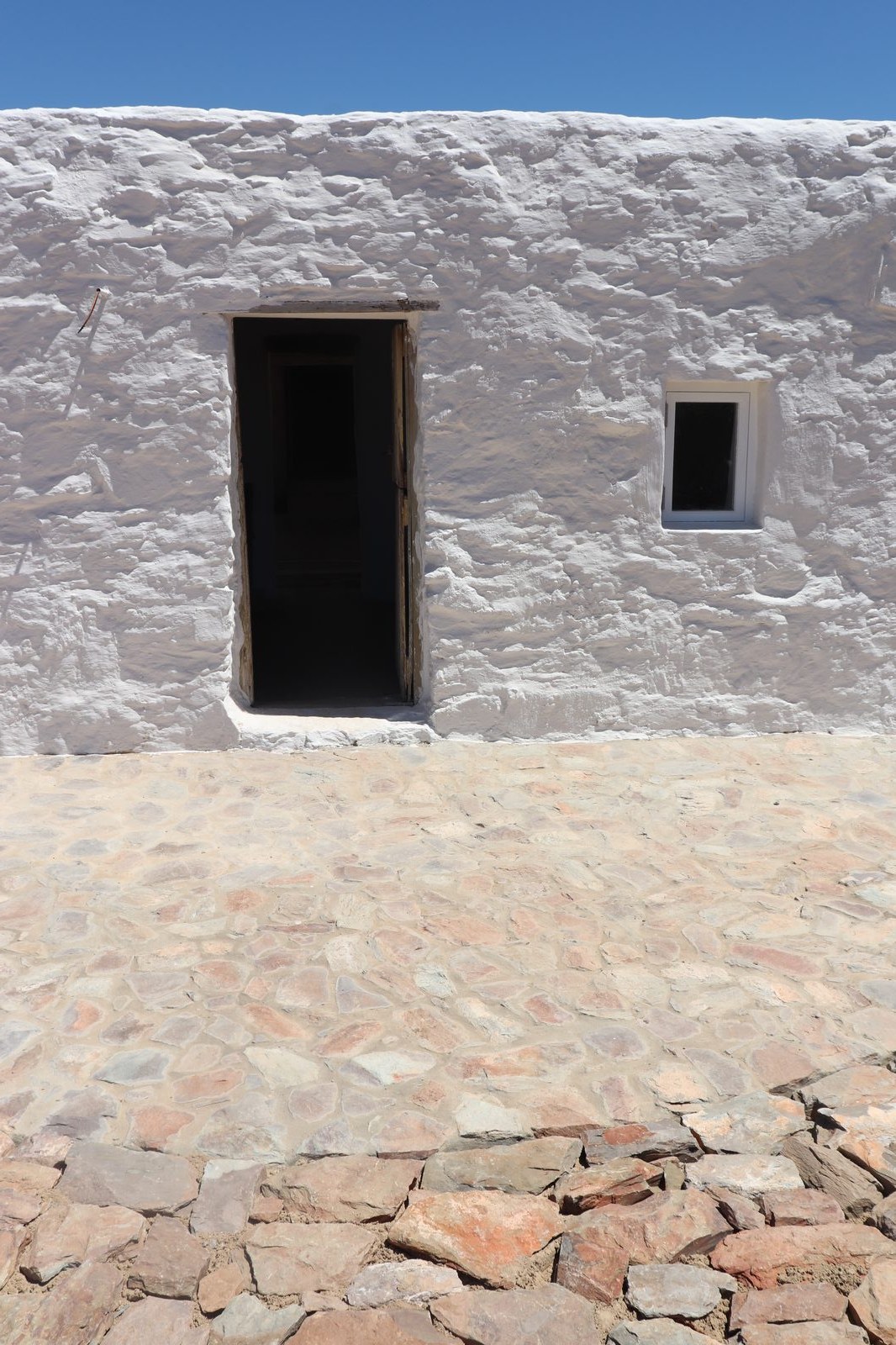 Skaapwagtershuisie — whitewashed stone wall, doorway and stone paving
