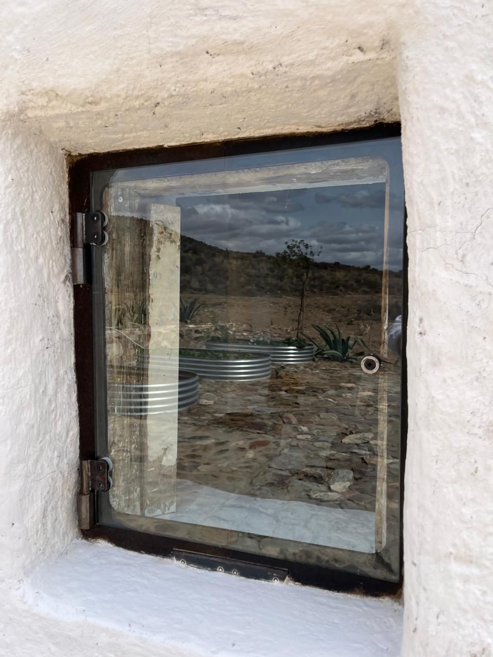 Small steel corner window — hinged glazing set into the whitewashed stone reveal, Skaapwagtershuisie