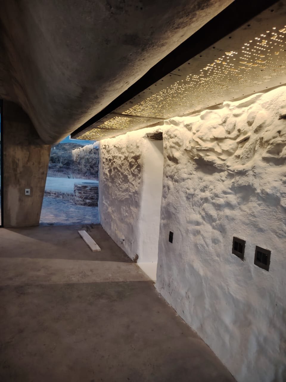 Decorative ceiling glowing — integrated light washing the rough stone wall